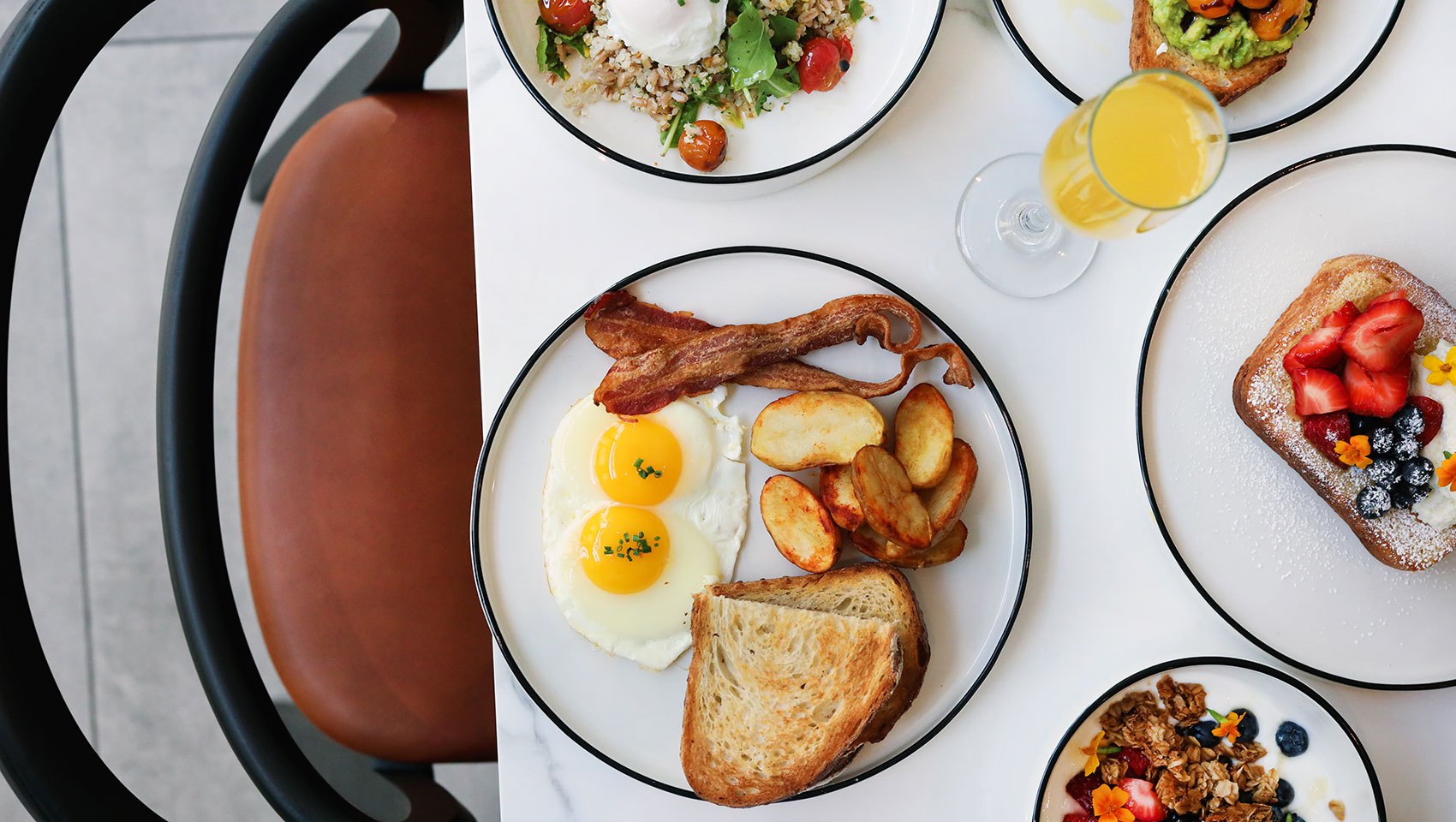 Multiple breakfast plates, including the quinoa bowl, avocado toast, brioche french toast, and yogurt dish.